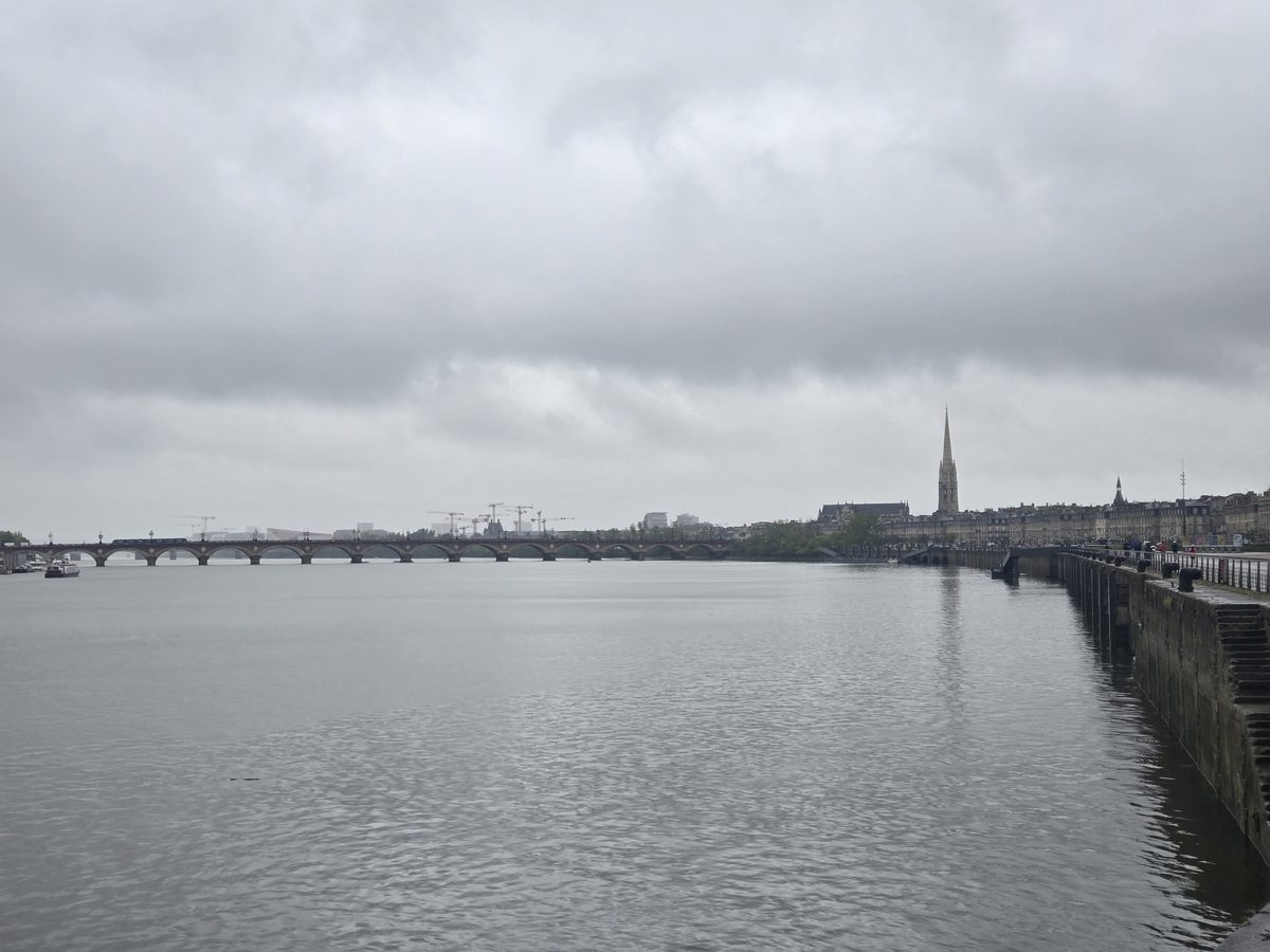 The Garonne riverfront with stone quay, bridge, and distant cathedral spire