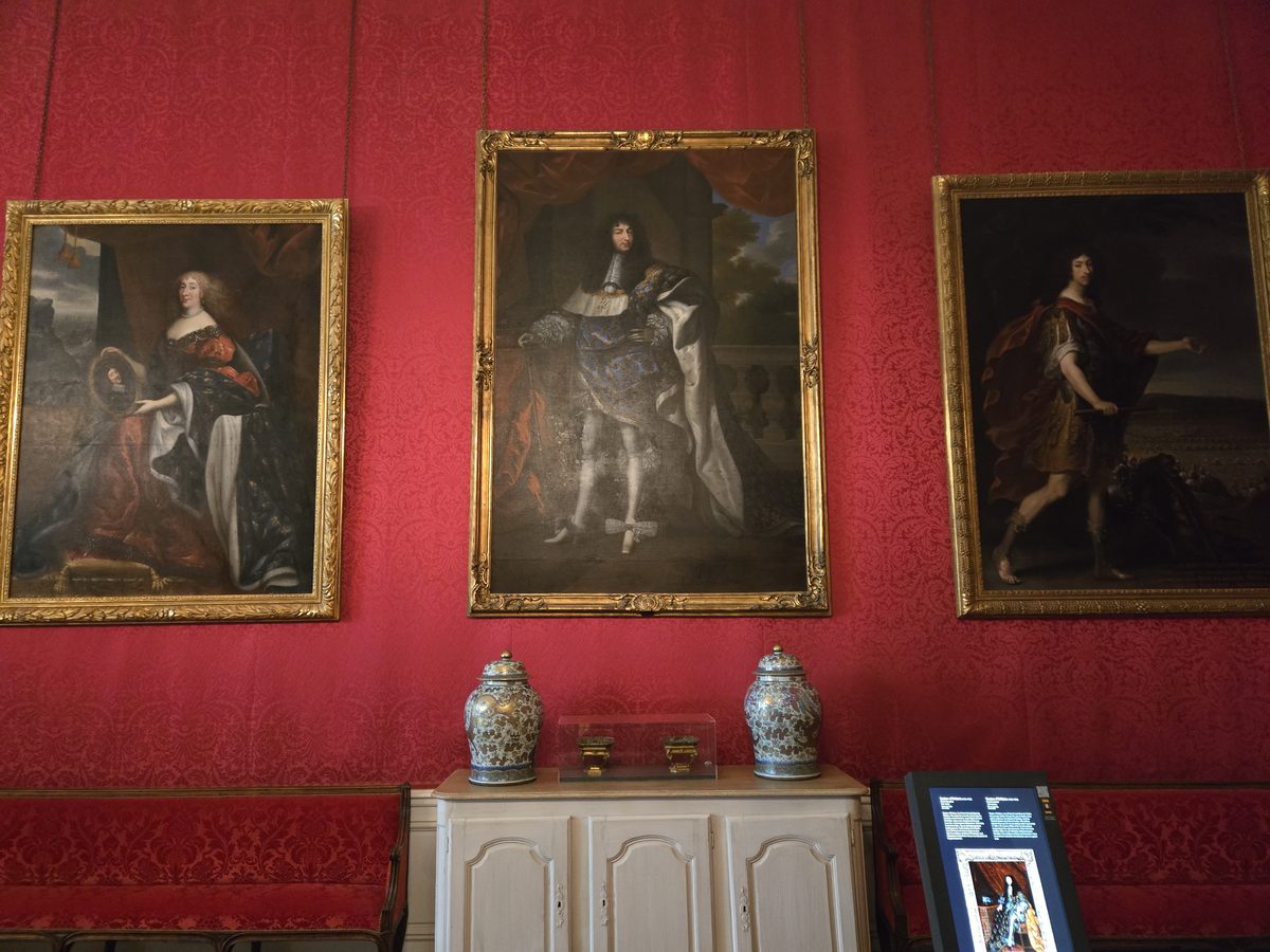 Portrait paintings of French nobility on burgundy walls