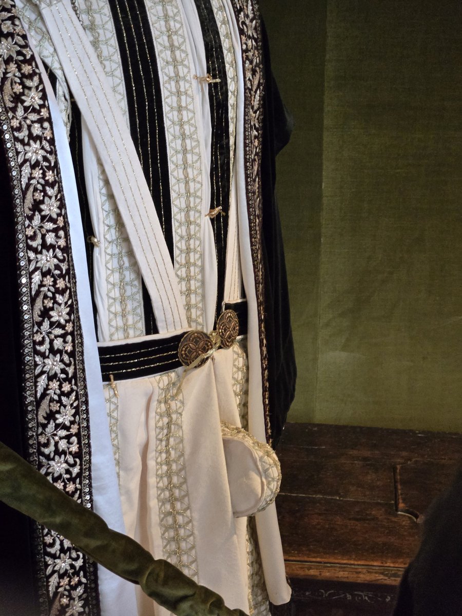 A Renaissance court robe displayed on a bed, featuring a prominent codpiece