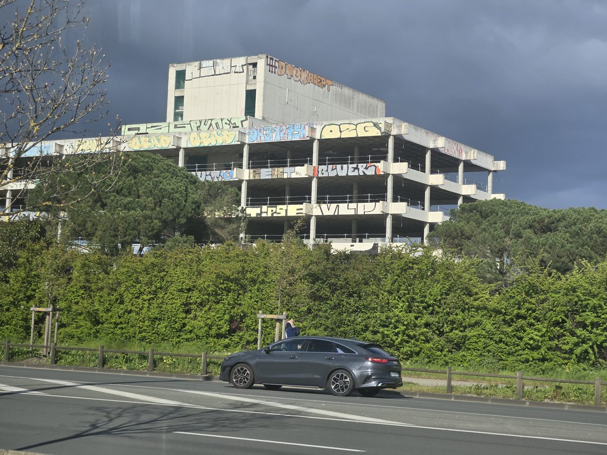 An abandoned parking lot with overgrown vegetation outside the Stade Atlantique