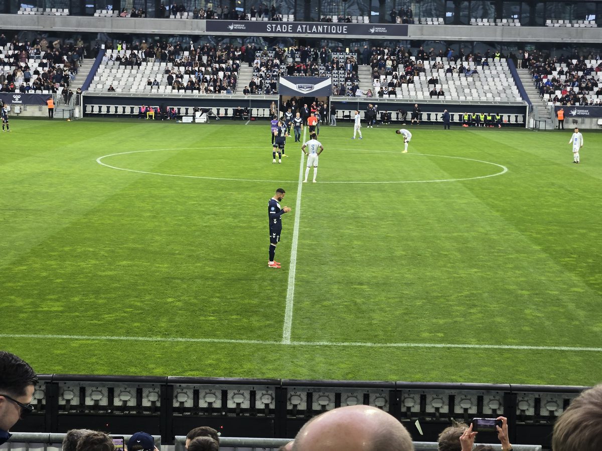 The pitch from above — players warming up, sparse crowd visible