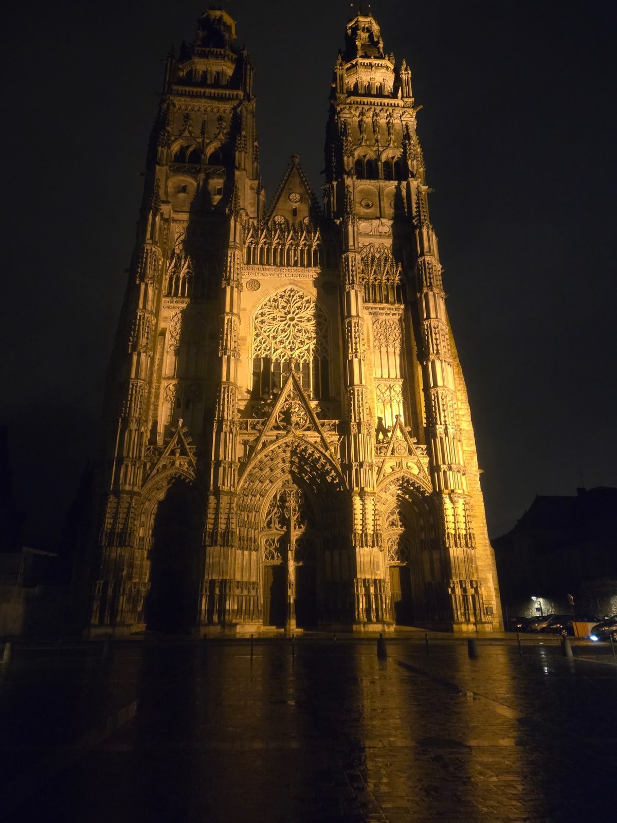 Tours Cathedral lit up at night in the rain