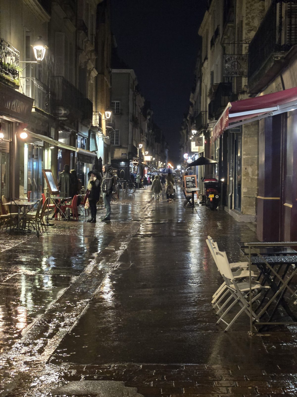 A rain-soaked Tours alley glowing under streetlamps