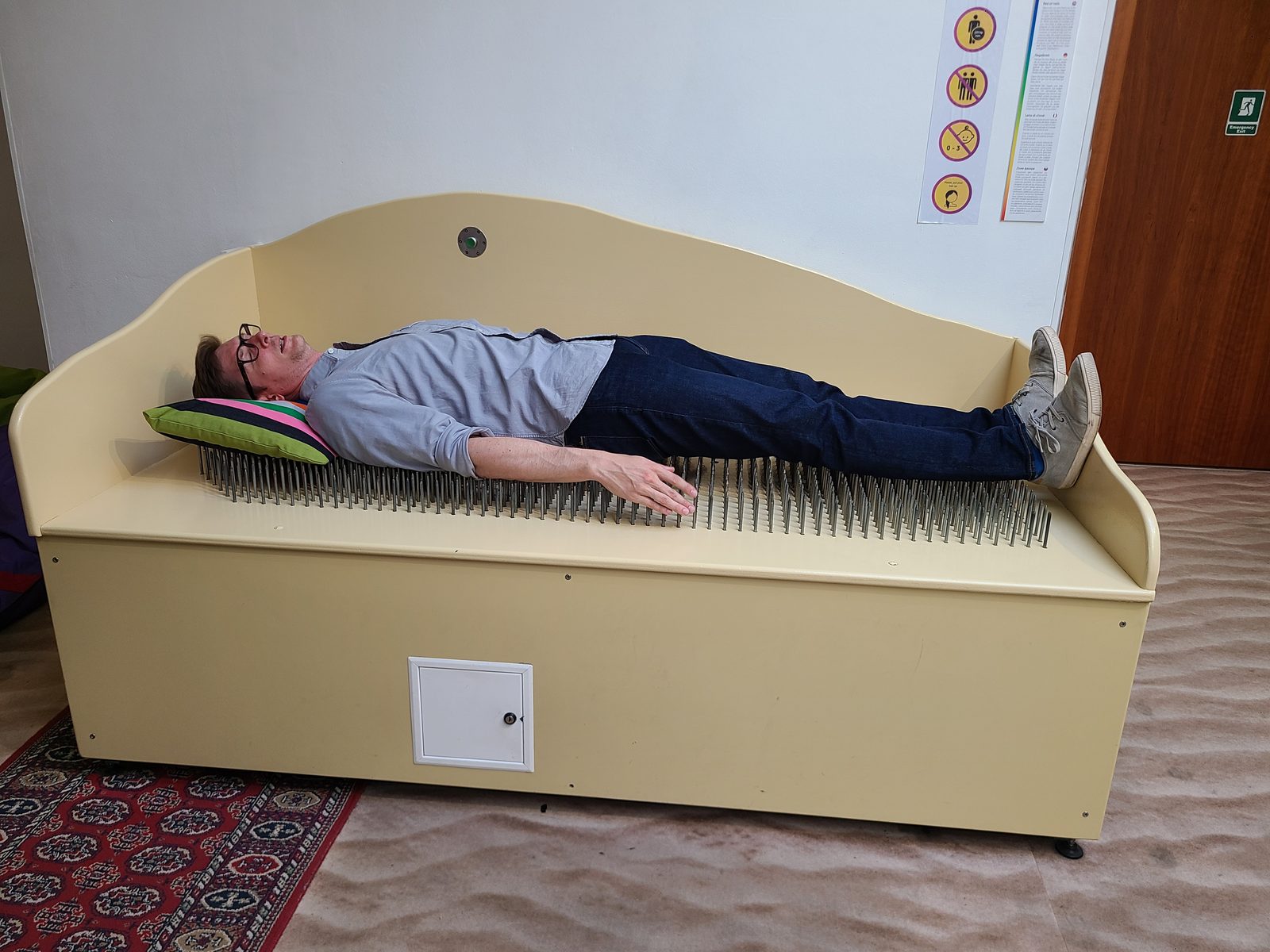 Erik lying on a bed of nails at a tourist museum