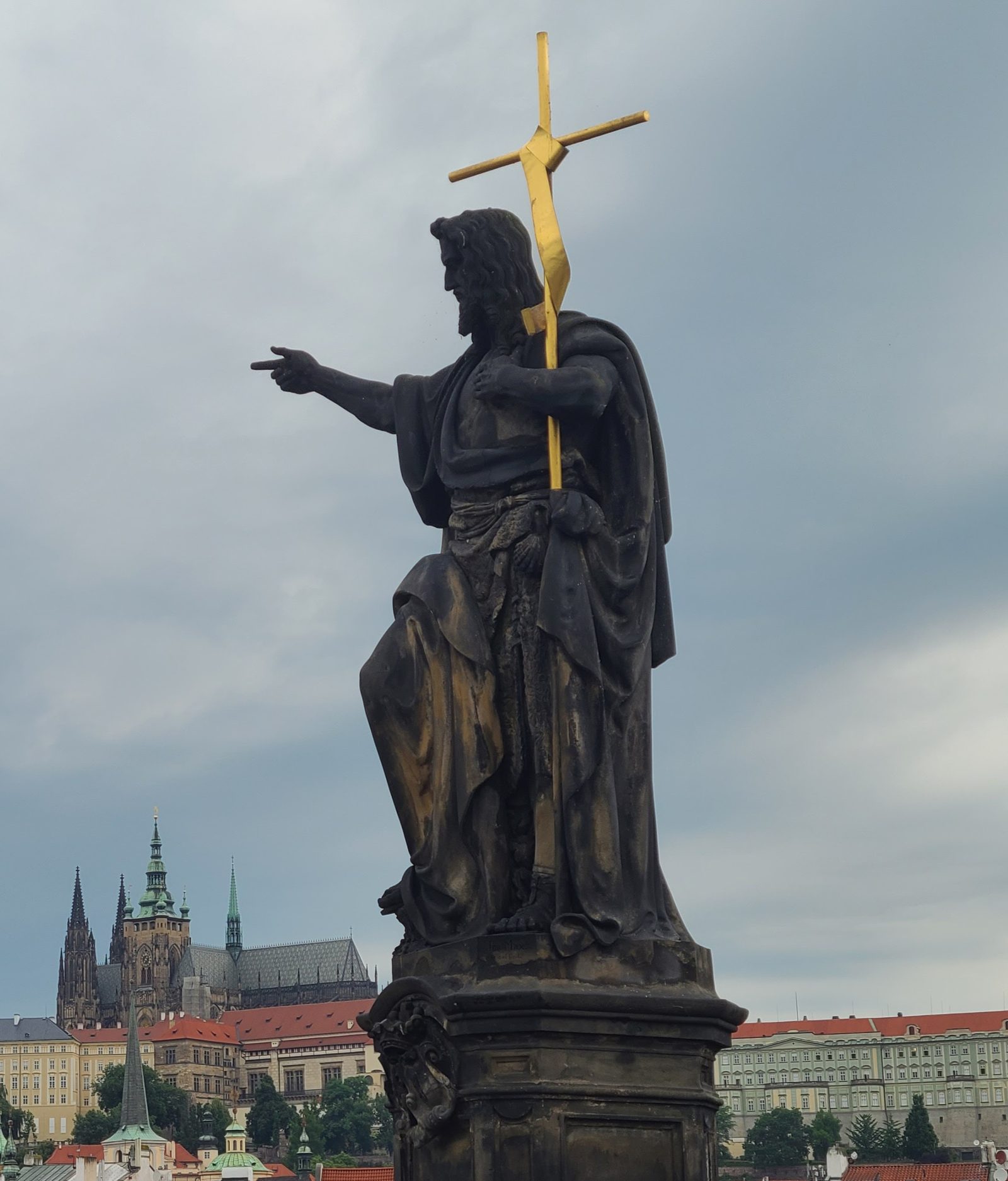 Statue on the Charles Bridge pointing toward Prague Castle
